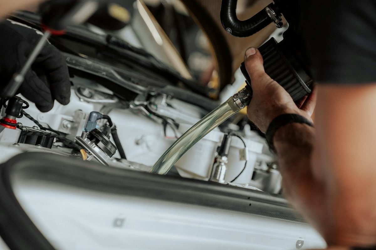 Mechanic topping up engine oil under a bonnet