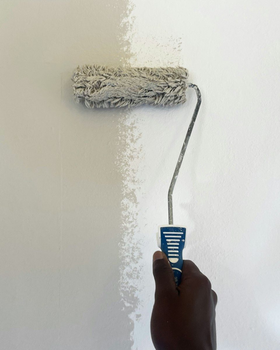 A painter on a ladder cutting in a wall