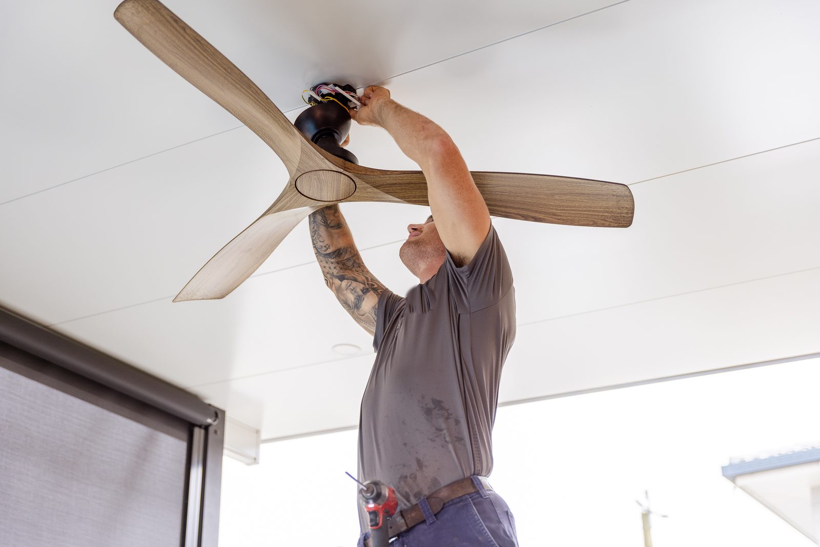 An electrician wiring a ceiling fan on a patio