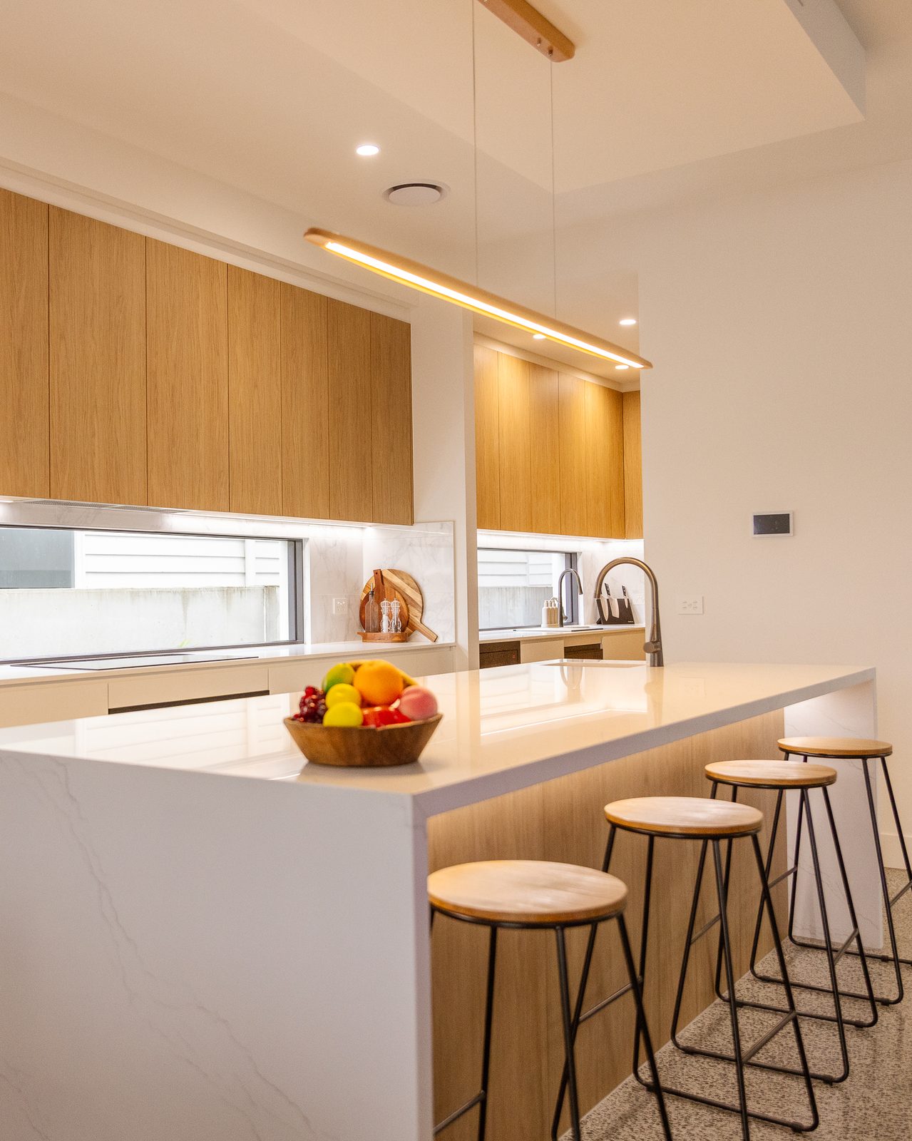 A renovated kitchen with a stone island, timber cabinetry and bar stools
