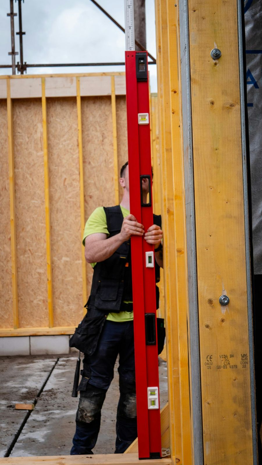 A carpenter checking a timber frame with a spirit level