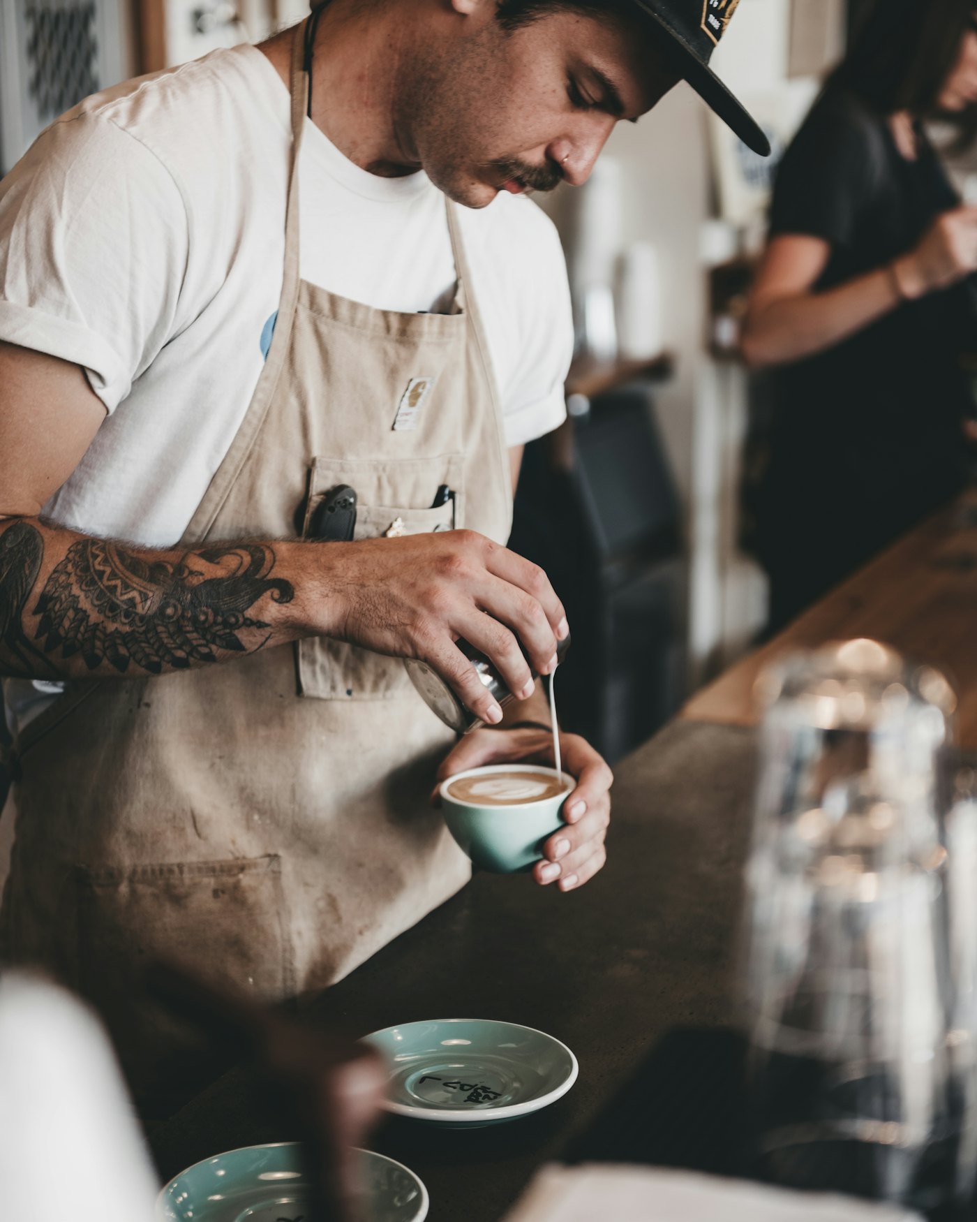 A barista pouring coffee in a busy café